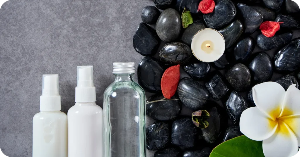 Realsa Indonesian Virgin Coconut Oil for cosmetic and spa applications, displayed with black stones and frangipani flower