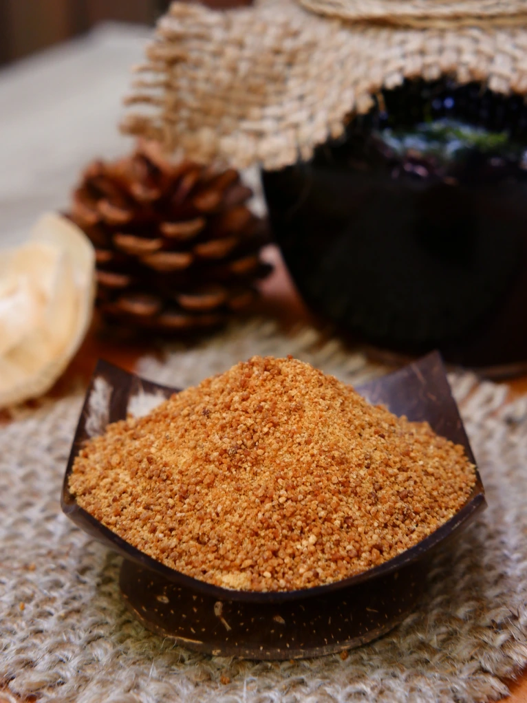 Natural coconut sugar in coconut shell bowl by Realsa, Indonesia, surrounded by rustic organic elements