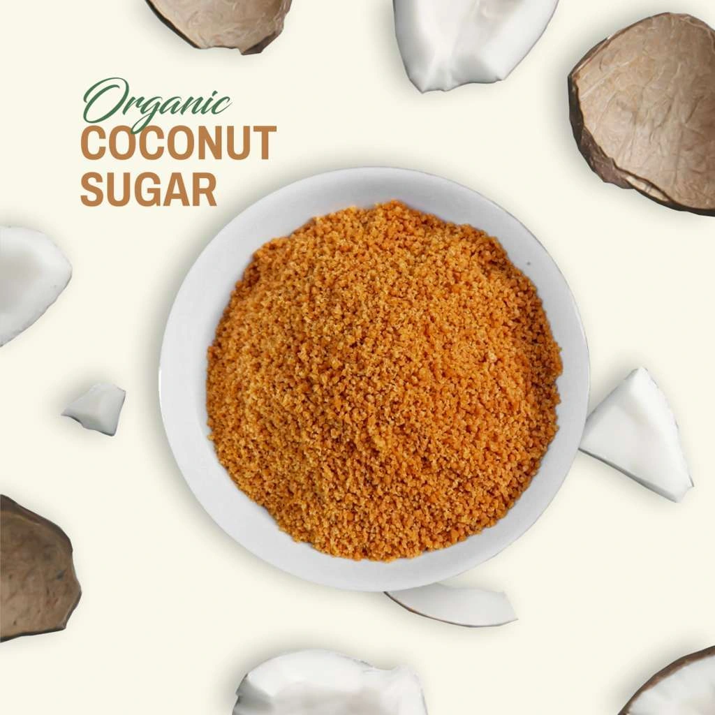 A white bowl filled with Realsa granulated organic coconut sugar, surrounded by coconut pieces on a light background.