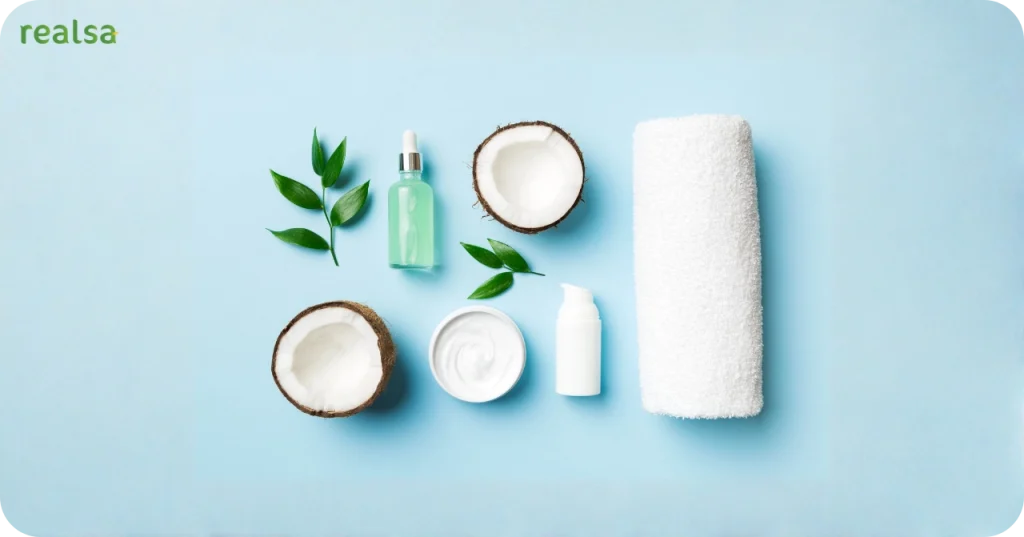 VCO for Cosmetic & Wellness Applications Cosmetic setup with white towel, serum bottle, coconut cream, and fresh coconut halves on a blue background, illustrating Virgin Coconut Oil beauty applications.