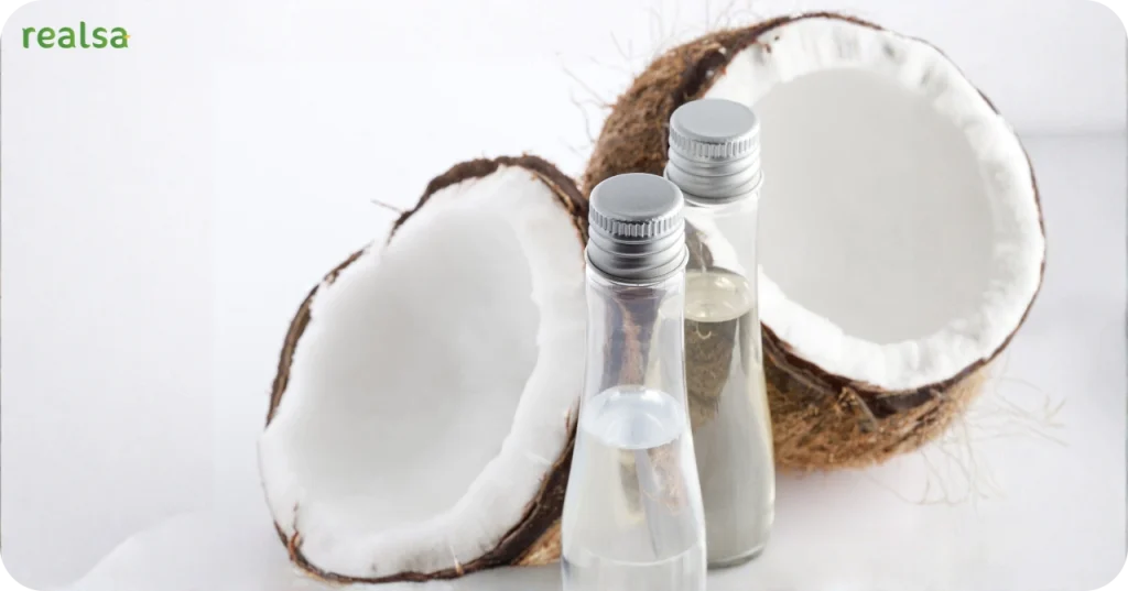 Clear glass bottles containing pure VCO set against fresh white coconut meat, illustrating the cold-pressed production result.
