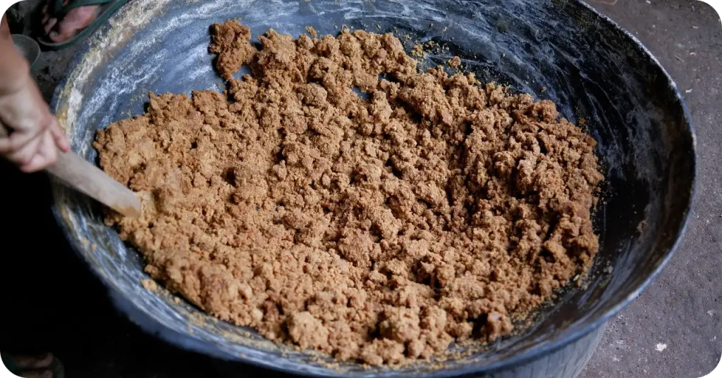 A producer stirring thickening coconut sap into granules, a critical processing step for buyers verifying moisture content control.