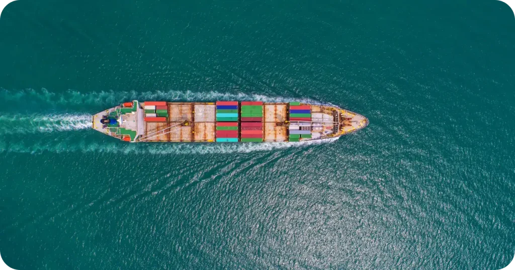 Top-down view of a fully loaded cargo ship navigating deep blue waters, representing the logistics capabilities of bulk exporters.