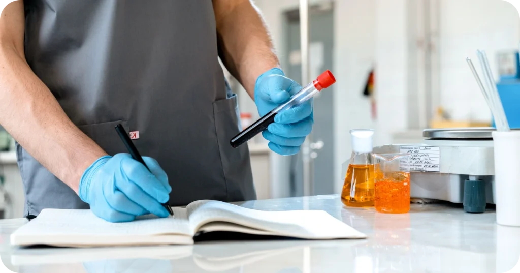 Close-up of a scientist holding a test tube and writing in a logbook, representing the rigorous quality control process of coconut oil exports.