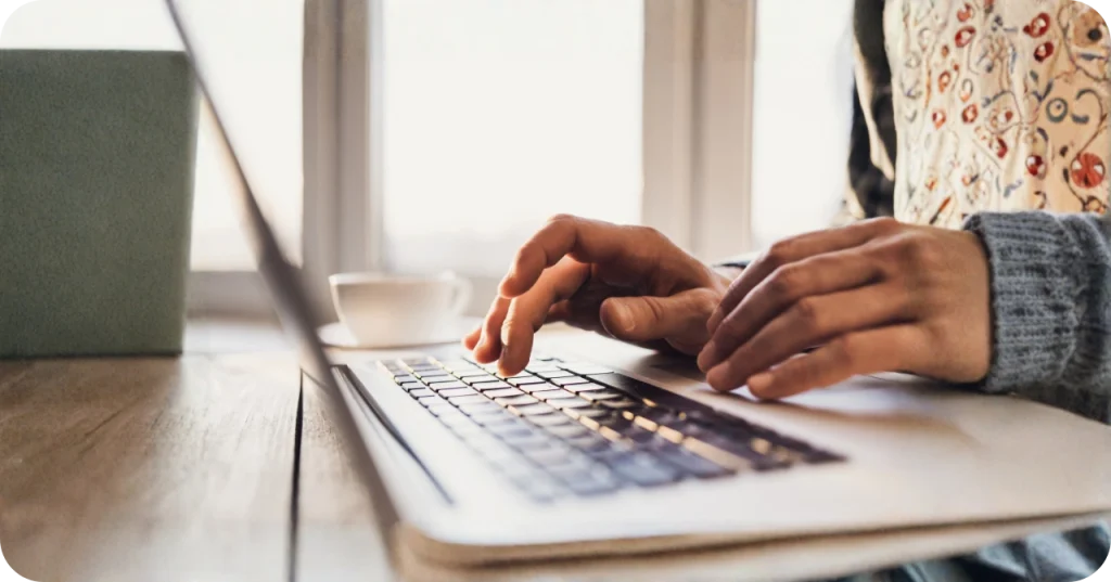 Close-up of hands typing on a laptop keyboard in a bright office setting, representing the administrative excellence of Indonesian vco supply partners.