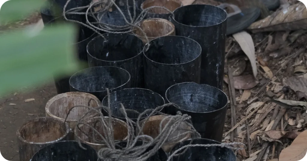 Reusable bamboo collection tubes (pongkor) resting on the ground, highlighting the eco-friendly tools central to agricultural sustainability in Indonesia.